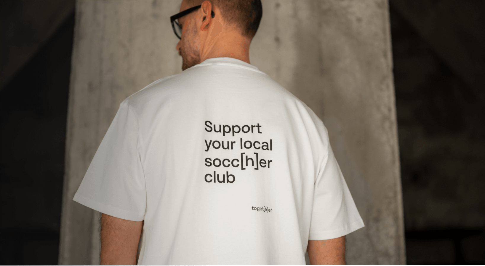 Person trägt weißes T-Shirt mit einem Motiv mittig auf dem Rücken