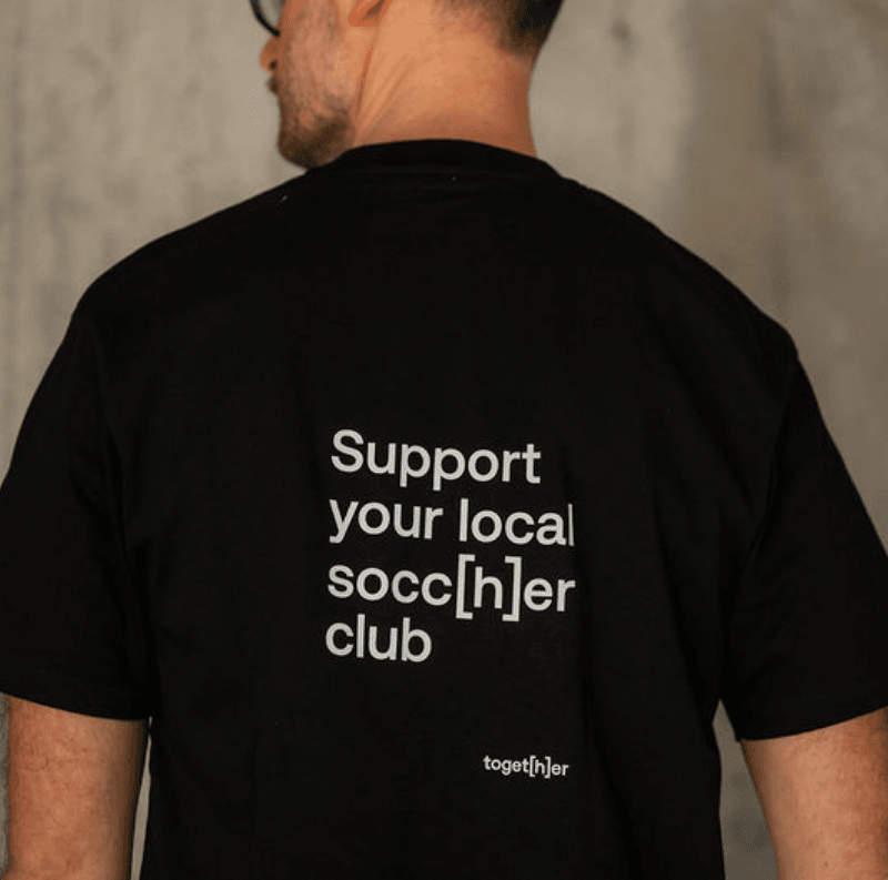 Person trägt schwarzes T-Shirt mit einem Motiv mittig auf dem Rücken
