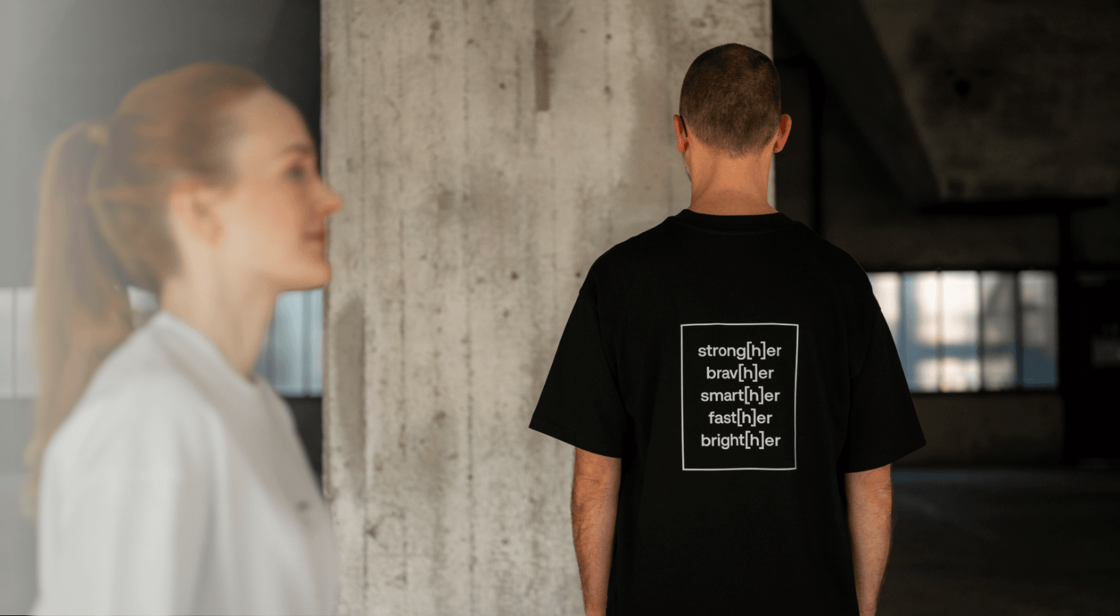Person trägt schwarzes T-Shirt mit einem typografischen Motiv auf dem Rücken
