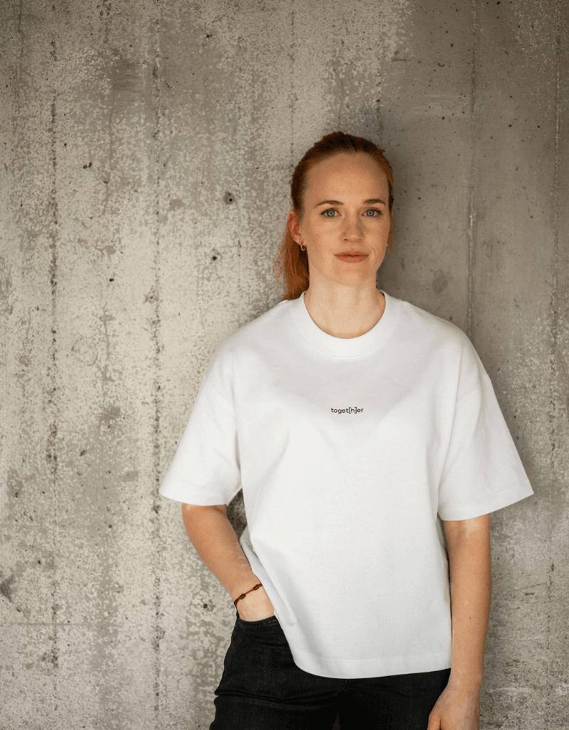 Person trägt weißes T-Shirt mit einem mit einem kleinen Logo toget[h]er auf der Brust