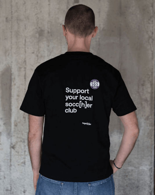 Person trägt schwarzes T-Shirt mit einem Motiv mittig auf dem Rücken