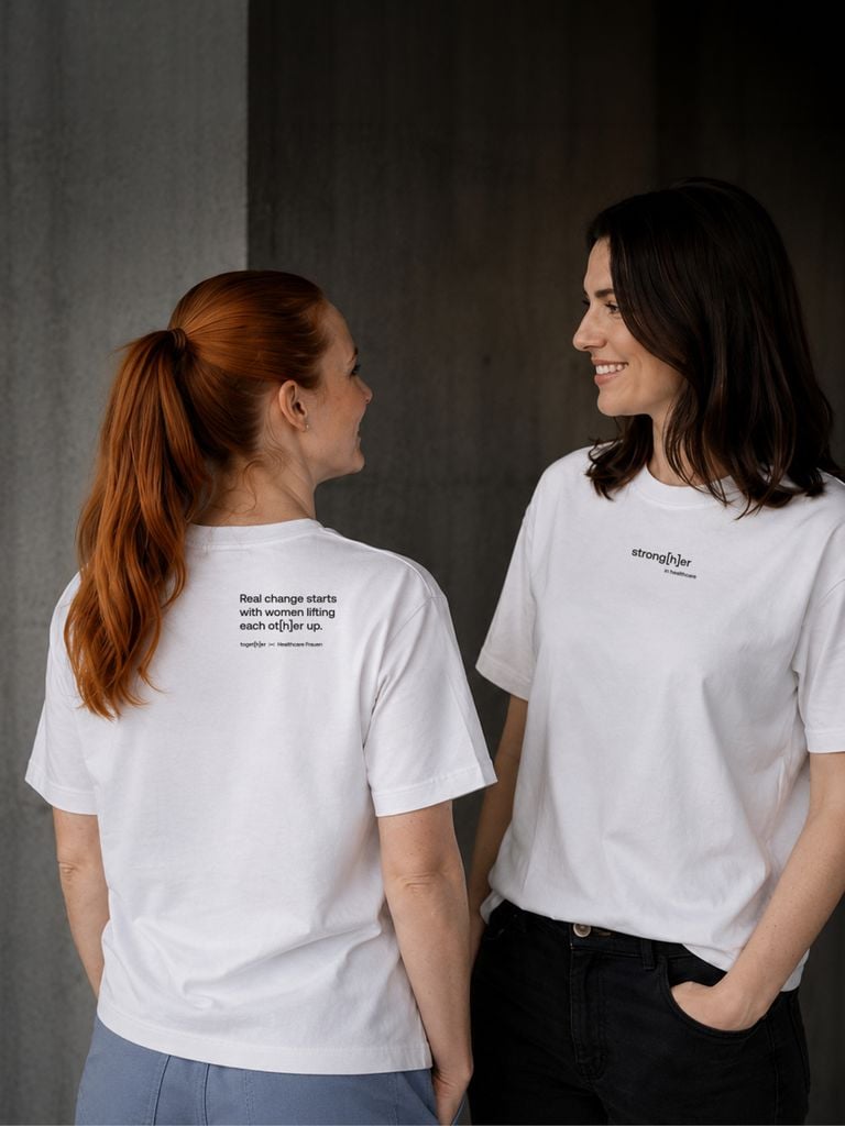 Personen tragen weißes T-Shirt mit Schriftzug „strong[h]er in healthcare“ 