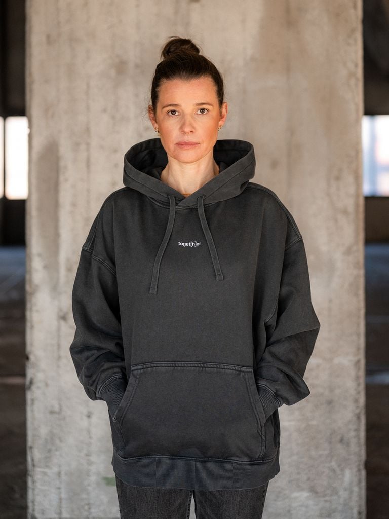 Frau trägt schwarzen Hoodie mit Schriftzug „toget[h]er“ auf der Brust