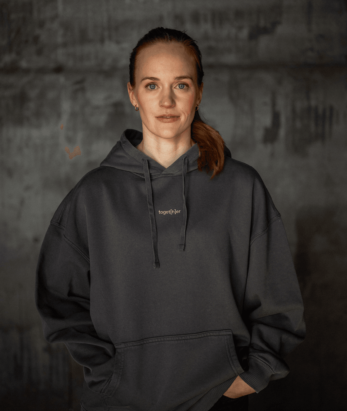 Frau trägt grauen Hoodie mit Schriftzug „toget[h]er“ auf der Brust