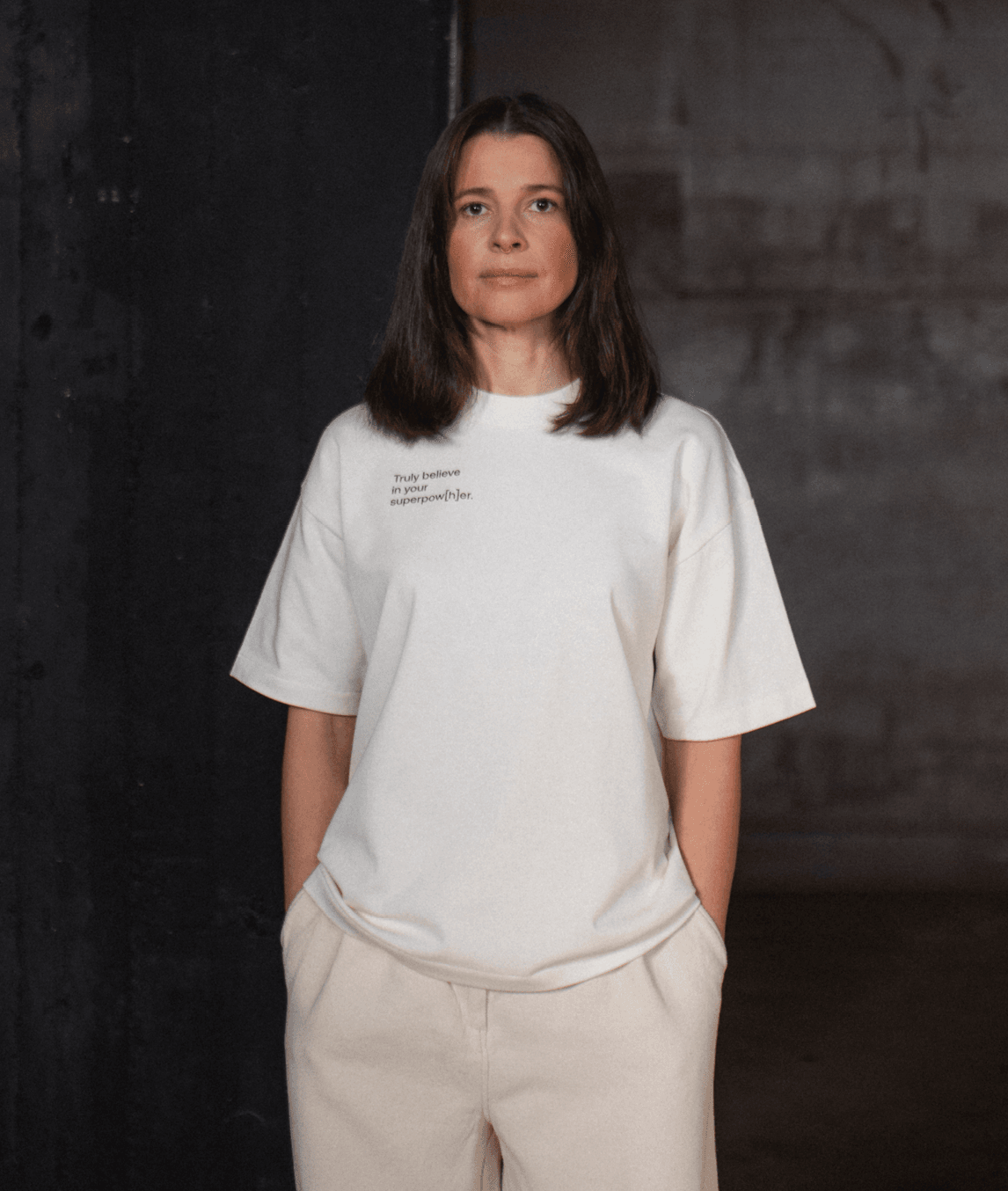 Frau trägt cream-farbiges T-Shirt mit Schriftzug „Truly believe in your superpow[h]er“ rechts auf der Brust
