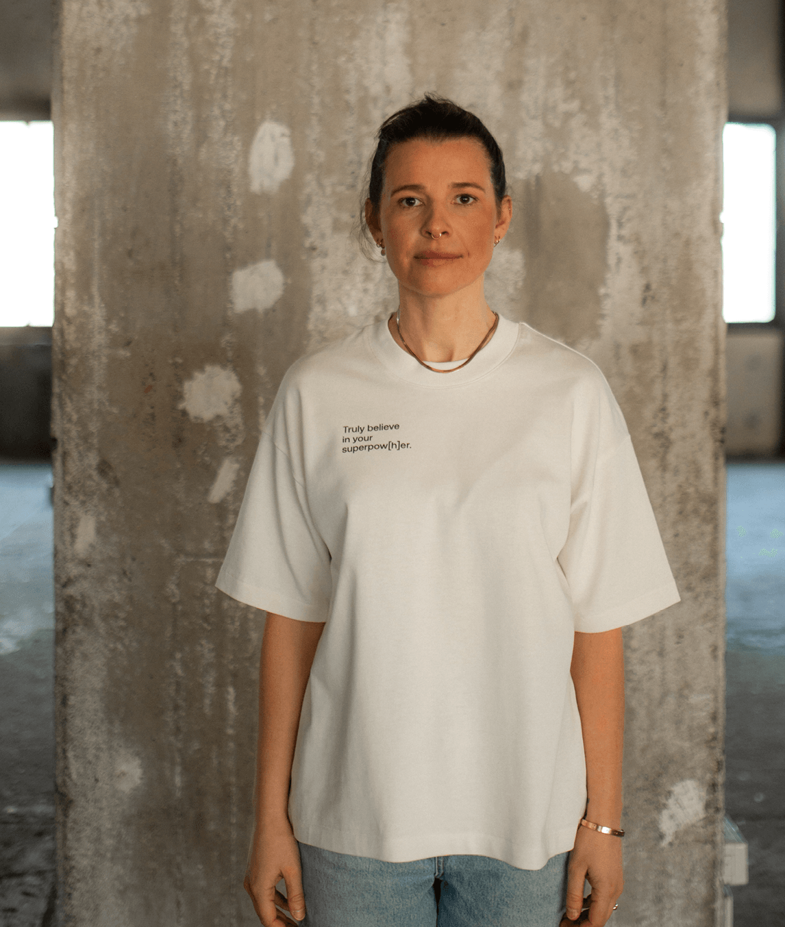 Frau trägt weißes T-Shirt mit Schriftzug „Truly believe in your superpow[h]er“ rechts auf der Brust