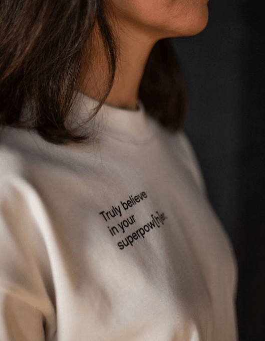 Detailaufnahme einer Person, die helles T-Shirt mit einem Schriftzug auf der Brust trägt